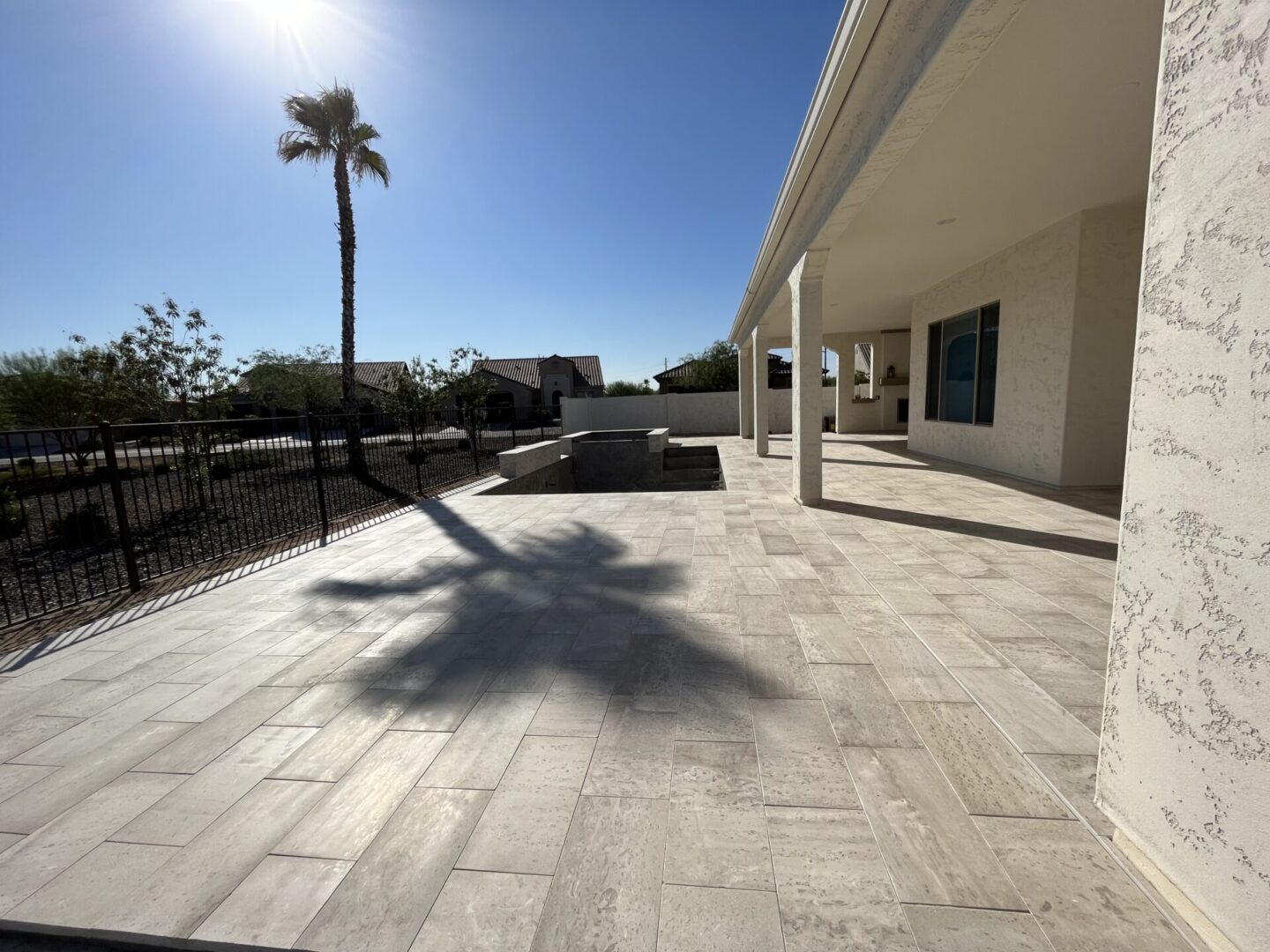 A white patio with a palm tree in the background.