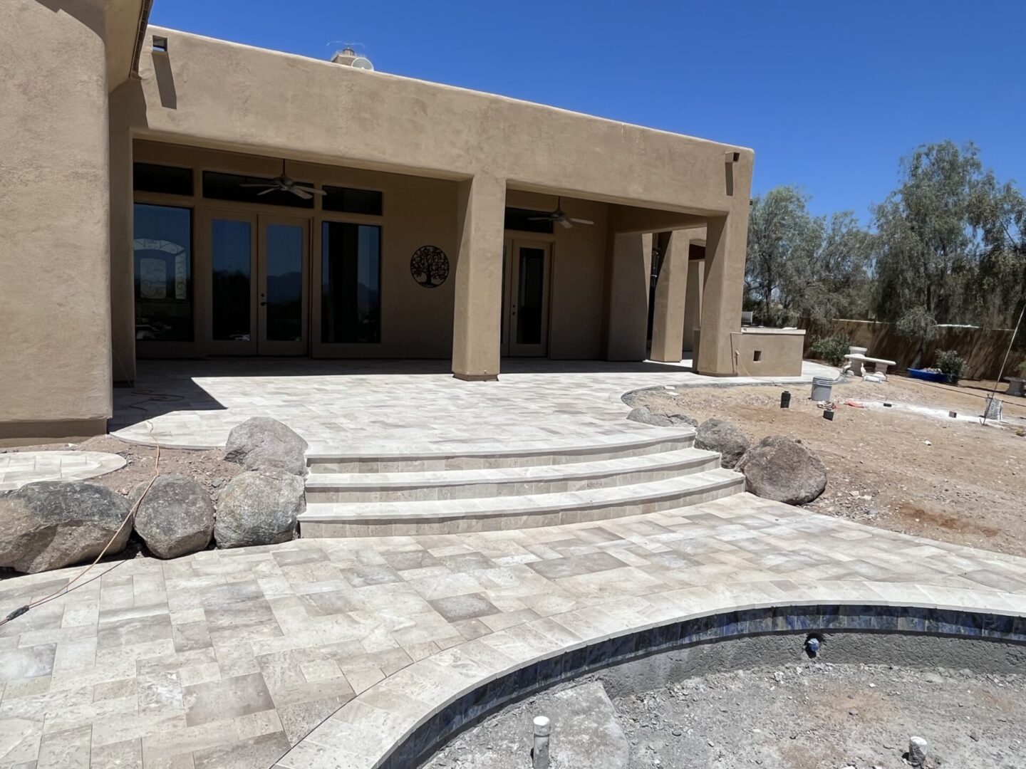 A patio with steps leading to a pool.