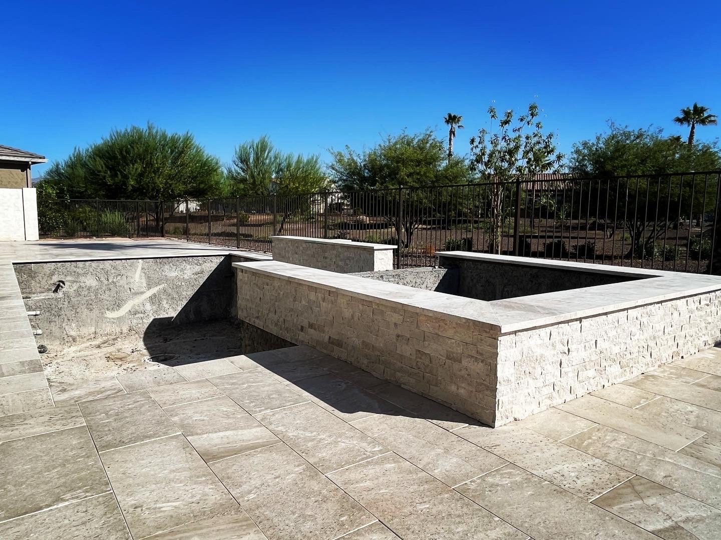 A backyard with a concrete patio and a pool.