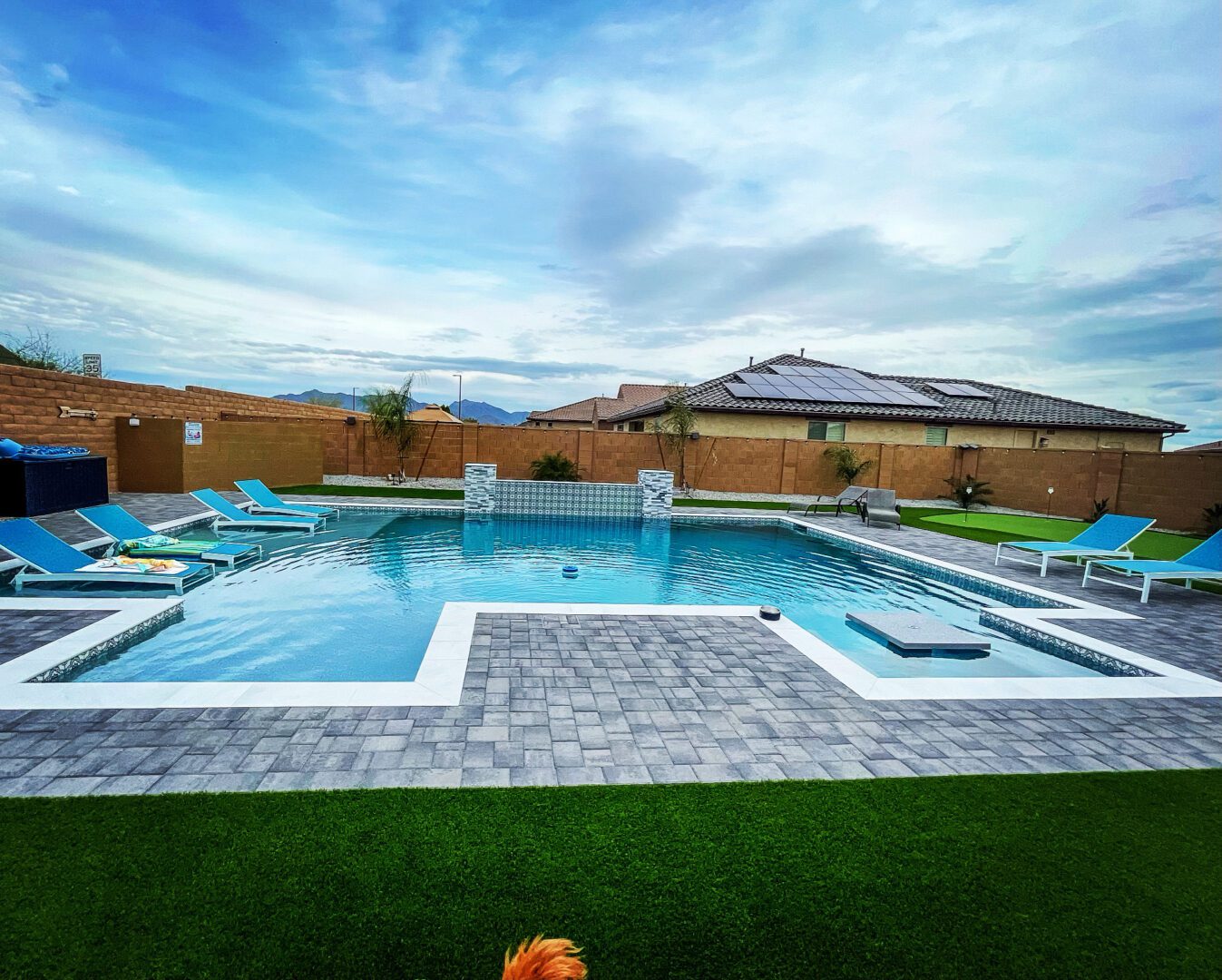 A backyard with a pool and lounge chairs.